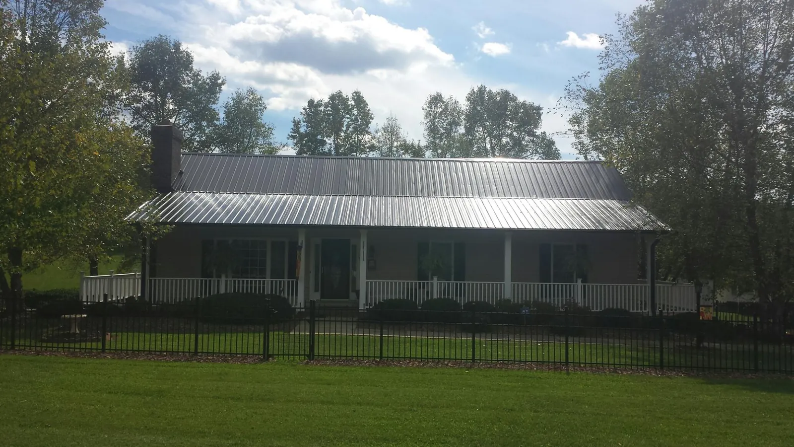 Gray metal roof on a brick ranch with a full width front porch — Gutter Guard Installation work by our crew in Gainesville