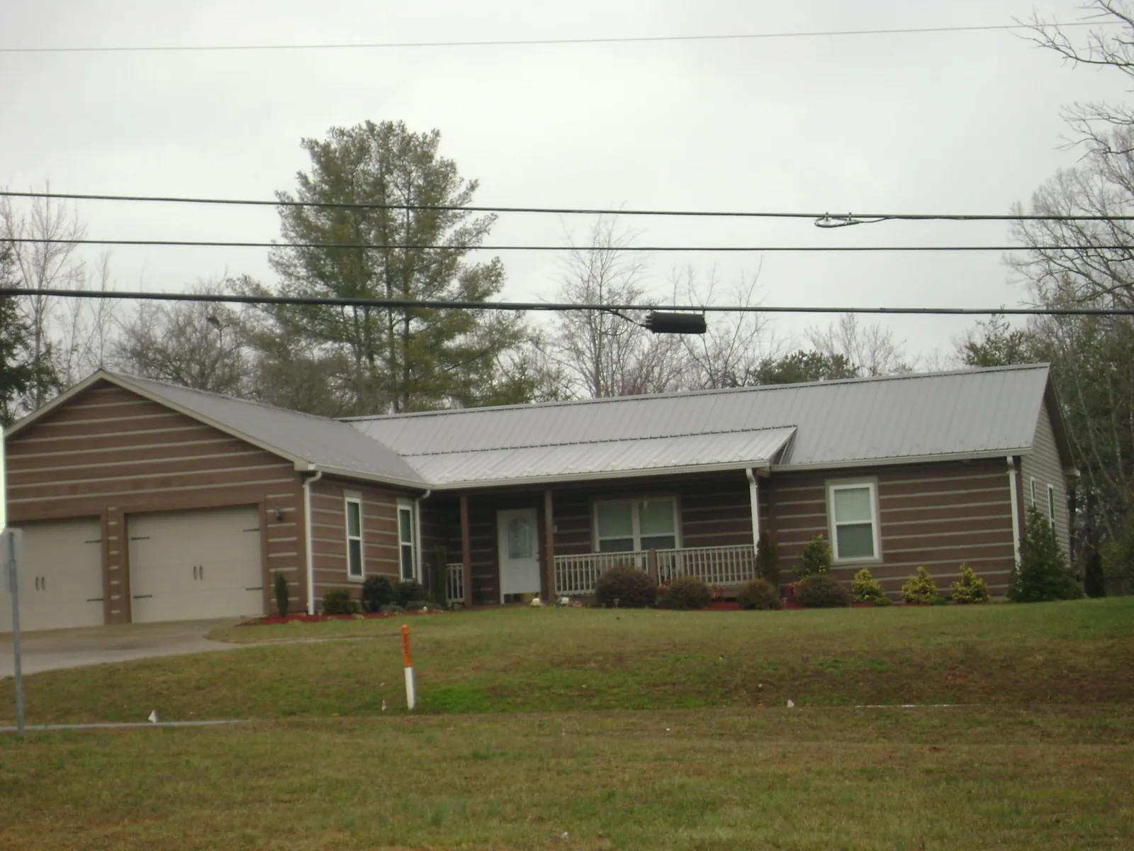 Gray metal roof on a log sided ranch home with a front porch in Gainesville